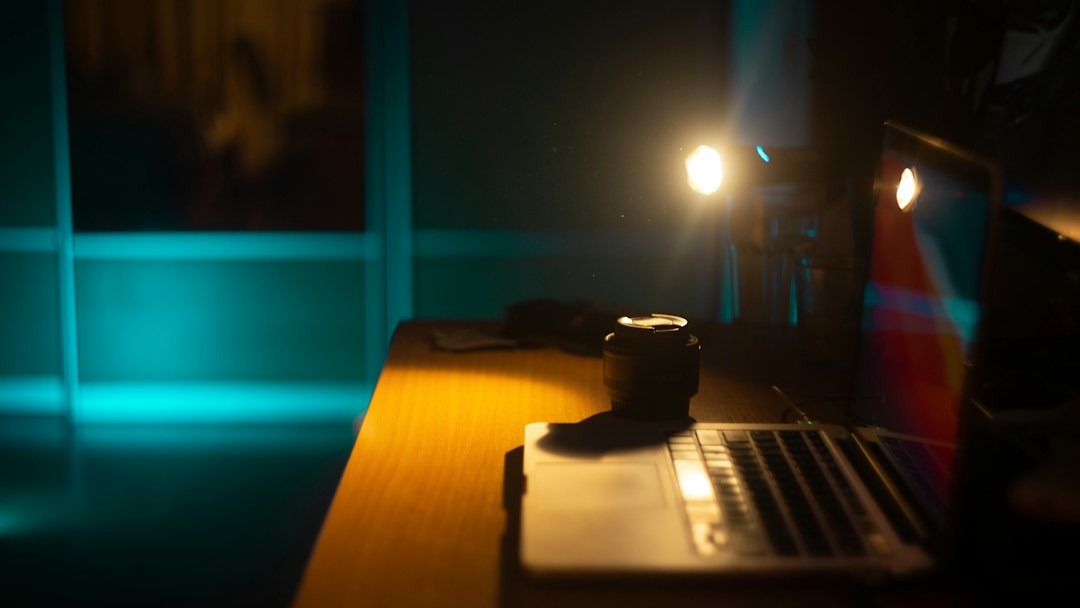 Camera and laptop on a desk in low light