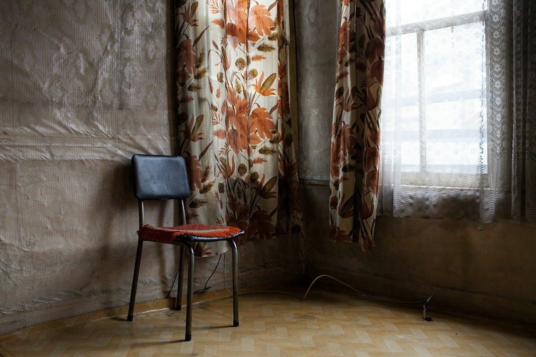 Single chair beside a window with patterned curtains
