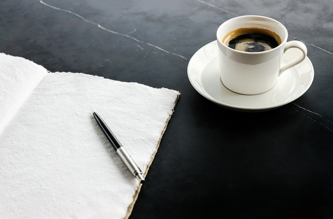 Contact CamXperience 1 Cup of coffee beside a blank notebook and pen